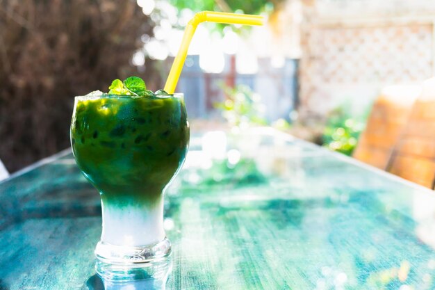 Groene ijsthee latte in glas op tafel in de tuin