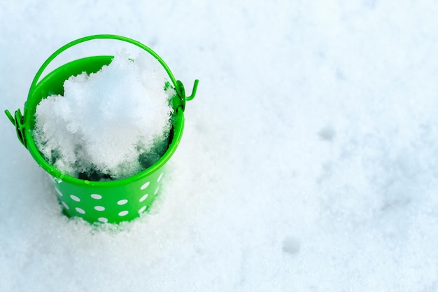 Groene ijzeren kleine emmer op sneeuwachtergrond