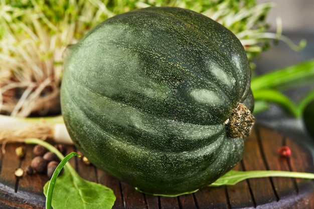 Groene Kabocha-pompoen met uien en knoflook op een houten rug. Gezond eten