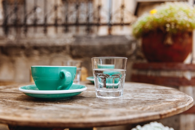 Groene keramische kopje cappuccino koffie op houten ronde tafel met glas water