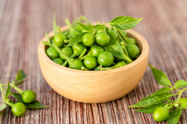 Groene kersenpeper in houten kom op lijst