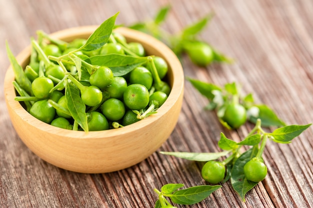 Groene kersenpeper in houten kom op lijst