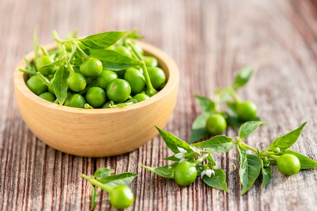 Groene kersenpeper in houten kom op lijst