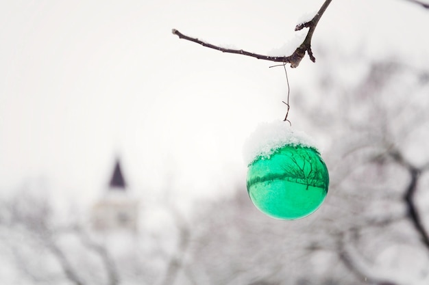 Groene kerstbal vintage glazen decoratie opknoping op boom buitenshuis vallende sneeuw winterlandschap achtergrond