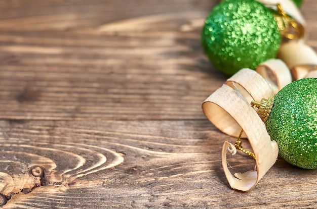 Groene kerstballen en houtkrullen op een houten ondergrond