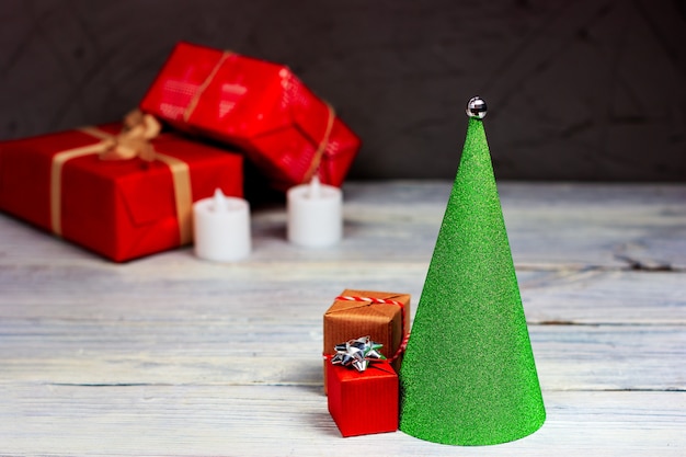 Groene kerstboom in de vorm van een kegel met rode geschenken op een licht houten tafel