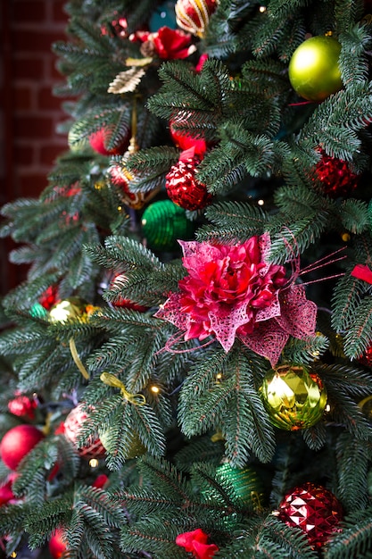 Groene kerstboom versierd met kerstcadeaus en een slinger.