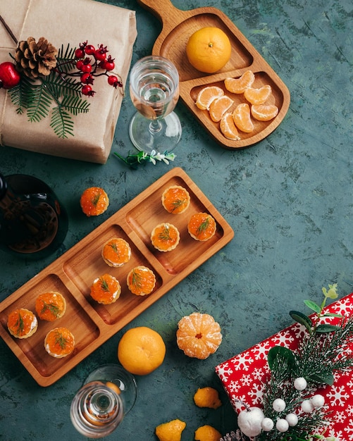 Foto groene kersttaartjes als achtergrond met rode kaviaarmandarijnen en champagne