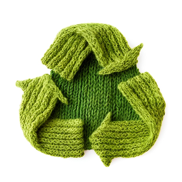 Groene kleur afvalrecycling symbool gemaakt van gebreide kleding op witte achtergrond