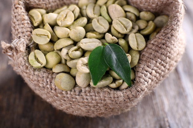 Groene koffiebonen in een zak op houten tafel