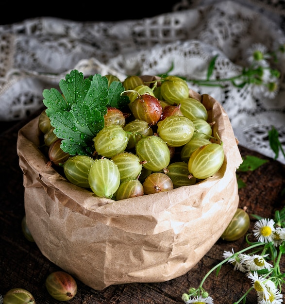 Groene kruisbessen in een papieren zak op een houten bord