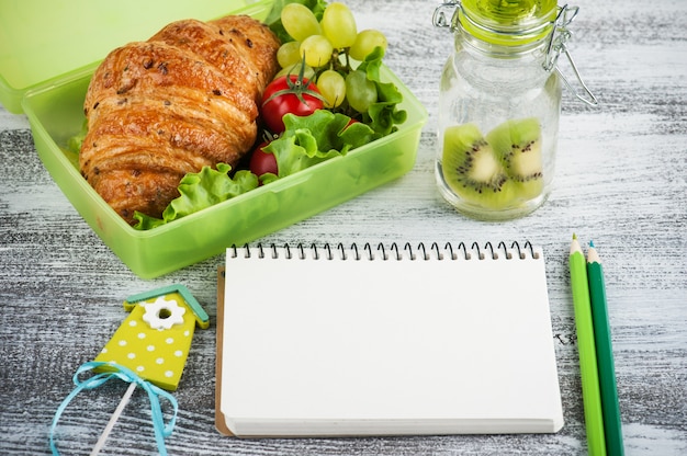 Groene lunchbox met croissant, salade