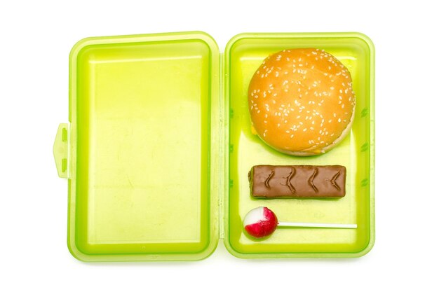 Foto groene lunchbox voor kinderen met ongezonde inhoud op witte achtergrond geïsoleerd