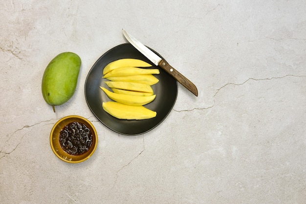 Groene mango en klaar om te eten op zwarte schotel met zoete vissaus op grungy cementvloer