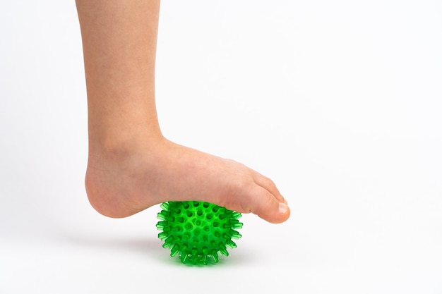 Groene naaldbal voor massage en fysiotherapie op een witte achtergrond met de voet van een kind