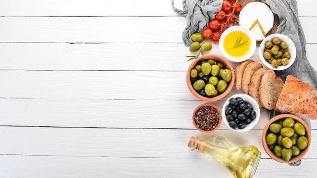 Groene olijven en zwarte olijven olie brood kaas en snacks Italiaanse keuken Op een witte houten tafel Bovenaanzicht Vrije ruimte voor tekst