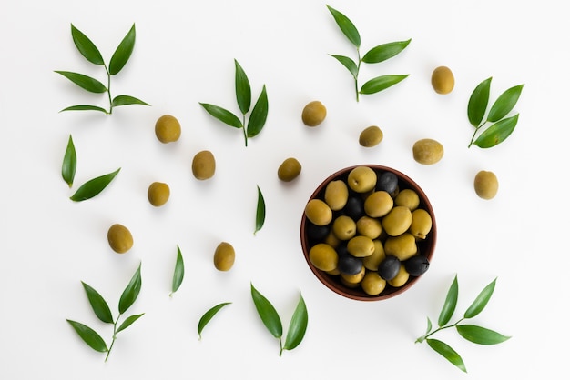 Foto groene olijven en zwarte peper in een kom bovenaanzicht