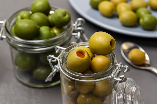 Groene olijven in glazen potten Olijven op een blauw bord