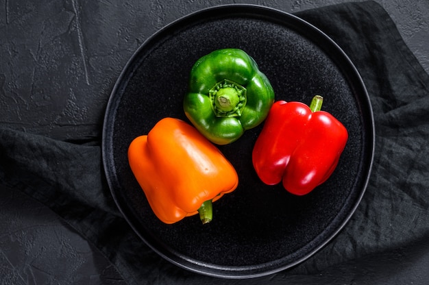 Groene, oranje en rode paprika op een bord.