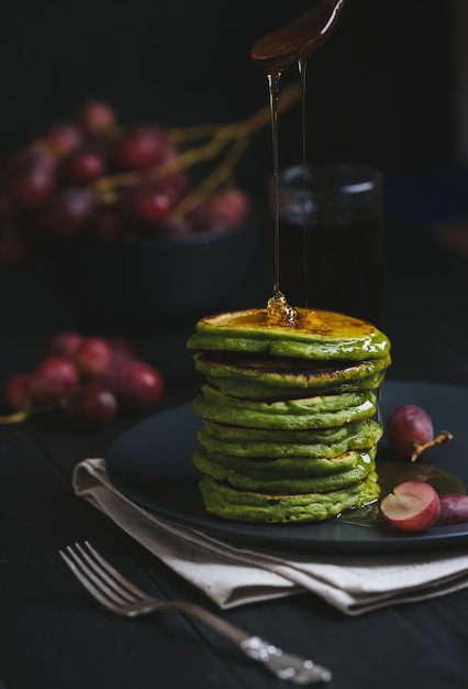 Groene pannenkoeken met matcha-thee of spinazie, opgemaakte honing en rode druiven