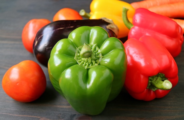 Groene paprika met andere kleurrijke groenten op houten achtergrond