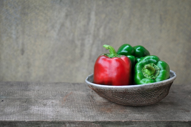 Groene paprika's groen en rood op houten achtergrond in retro zeef