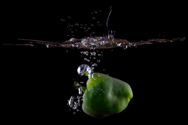 Groene paprika water splash op zwarte achtergrond