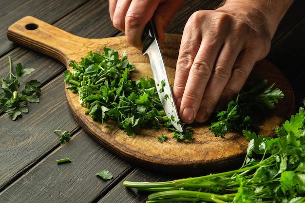 Groene peterselie snijden op een snijplank met een mes voor het koken van vegetarisch voedsel boerenvoedsel