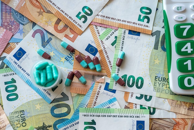 Groene pillen en capsules op stapel eurobankbiljetten. Geld of gezondheidszorg