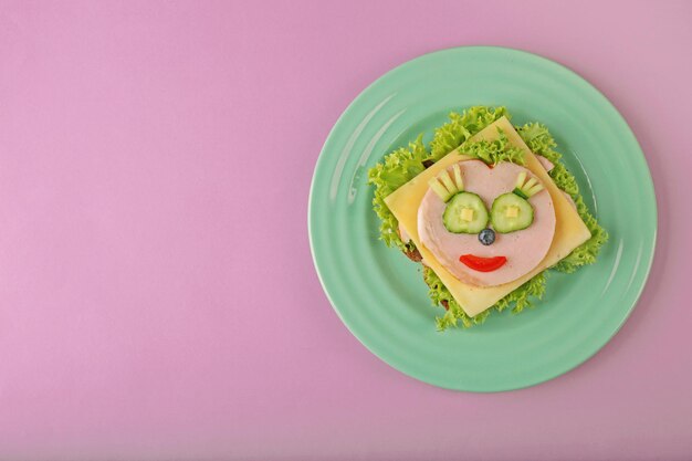 Groene plaat met grappige sandwich op roze achtergrond