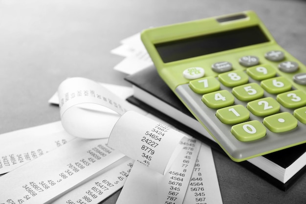Groene rekenmachine met rekeningen en notitieboekje op grijze achtergrond Belastingconcept