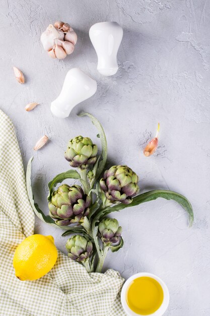 Groene rijpe rauwe artisjokken hoofden klaar om te koken. Artisjokken en ingrediënten knoflook, citroen en olijfolie