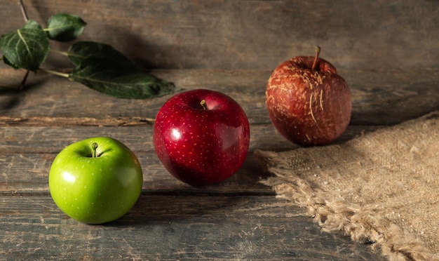 Groene rode en rotte appels op jute op houten planken