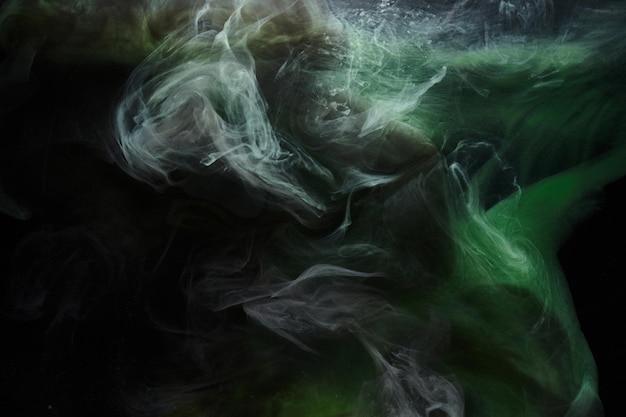 Groene rook op zwarte inktachtergrond, kleurrijke mist, abstracte wervelende smaragdgroene oceaanzee, acrylverfpigment onder water
