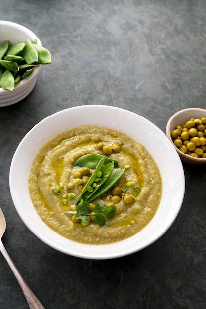 Groene roomsoep met groene verse erwten in witte plaat op donkere achtergrond Gezond veganistisch eten