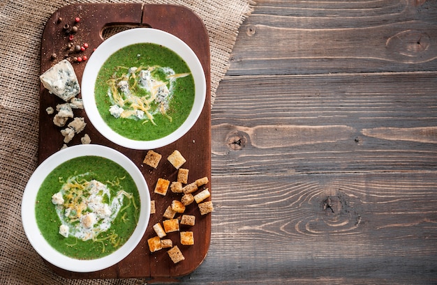 Groene roomsoep van spinazie en broccoli. met de toevoeging van Parmezaanse kaas en blauwe kaas met croutons. een houten oppervlak.