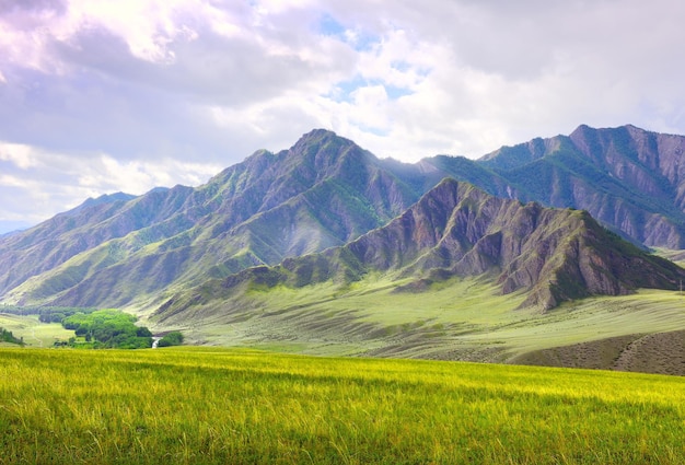 Groene rotsachtige bergen in de zomer onder een bewolkte blauwe hemel Siberië Rusland