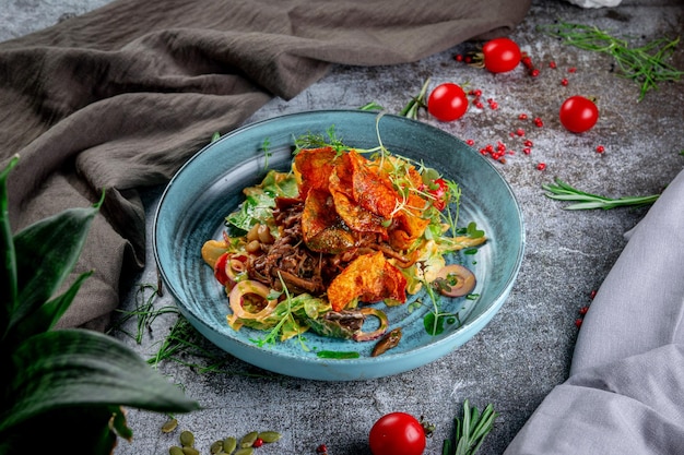 Groene salade met gebakken aardappelchips tomaten champignons en rundvlees met rode uienringen en rucola