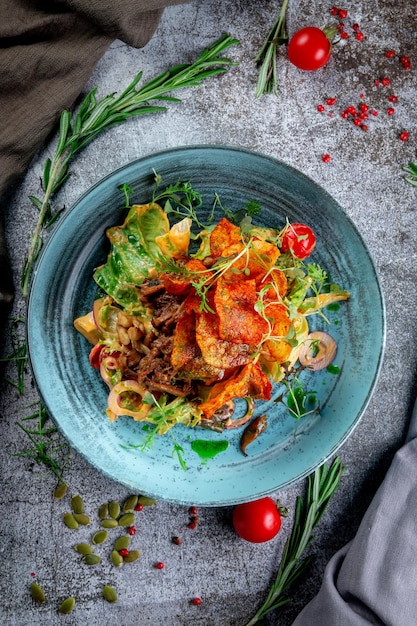 Groene salade met gebakken aardappelchips tomaten champignons en rundvlees met rode uienringen en rucola