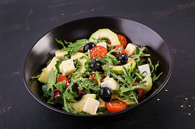 Groene salade met gesneden avocado, cherry tomaten, zwarte olijven en kaas