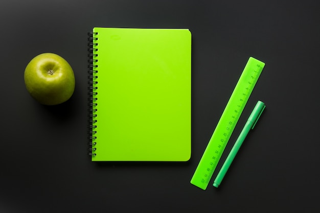 Groene schoolbenodigdheden, notebooks op zwart. Bovenaanzicht
