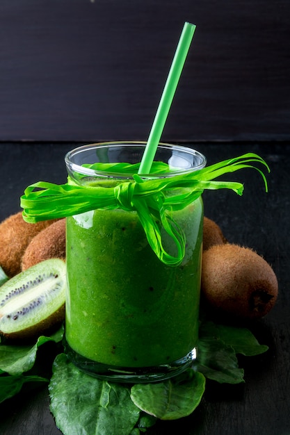 Groene smoothie dichtbij ingrediënten voor het op zwarte houten. Kiwi en spinazie. Detox. Gezond drankje.