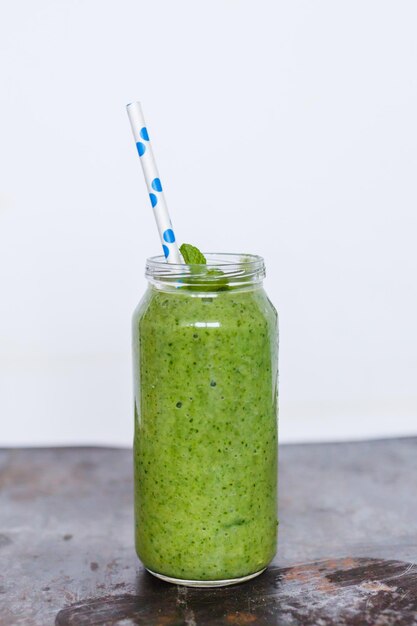 Groene smoothie in glas met gestreept rietje op de donkere tafel