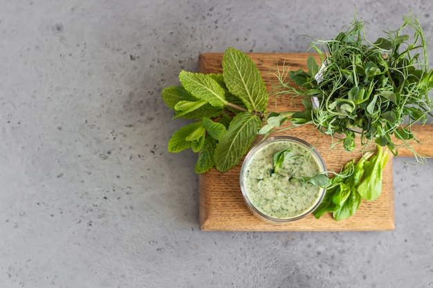 Groene smoothie met spinazie, munt en jonge spruit microgroen op een houten bord