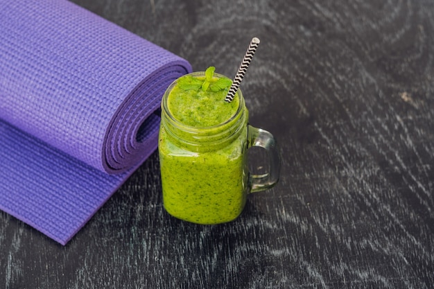 Groene smoothie met stro en een yogamat