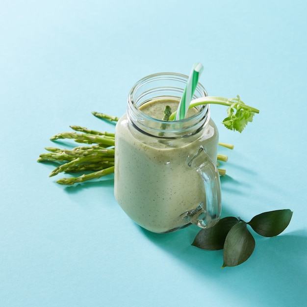 Groene smoothie van groene biologische groenten met asperges en selderij in een glazen kom op groen
