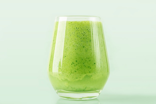 Groene smoothie van spinazie, appel, komkommer en sojamelk in glas geïsoleerd op groene achtergrond