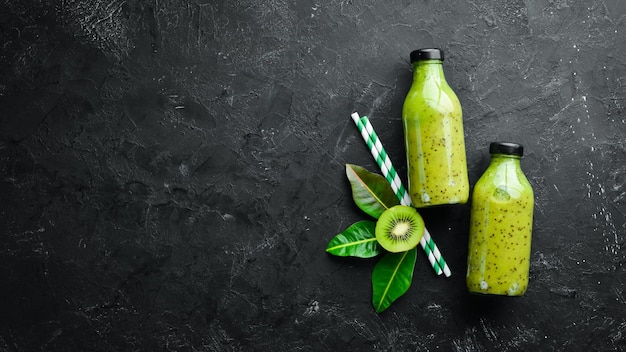 Groene smoothies met verse kiwi en kiwi op een zwarte achtergrond Houten rustieke stijl Fruit Bovenaanzicht Vrije ruimte voor tekst