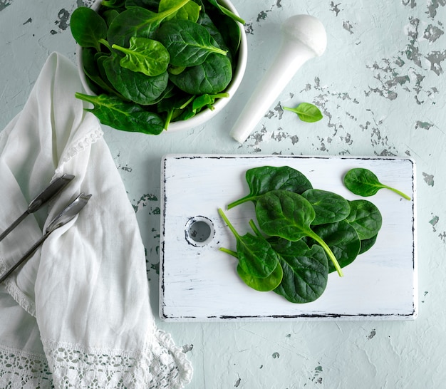 Groene spinazie bladeren op een witte houten bord