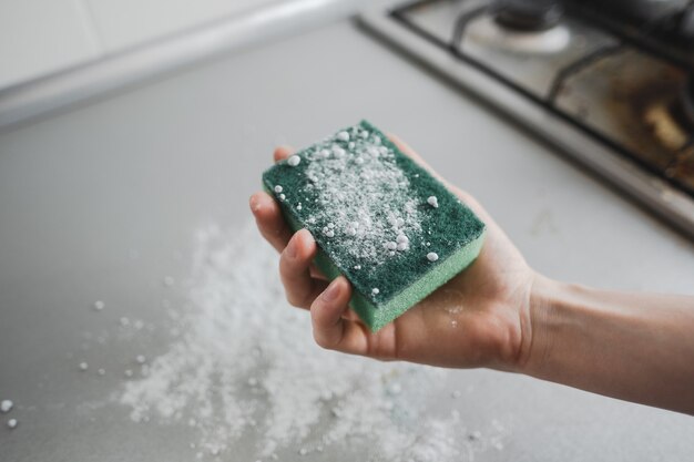 Foto groene spons met een in hand reinigingspoeder, keuken het schoonmaken